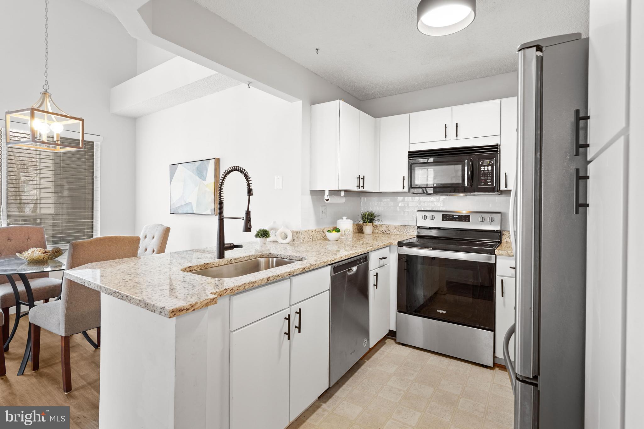 11731 Summerchase Circle, Unit 1731E Reston, VA 20194 - Photo 7 of 30 a kitchen with stainless steel appliances granite countertop a sink stove and refrigerator