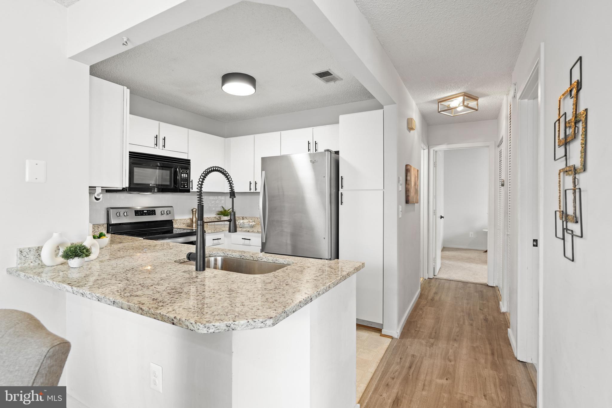 11731 Summerchase Circle, Unit 1731E Reston, VA 20194 - Photo 8 of 30 a kitchen with granite countertop a sink refrigerator and microwave