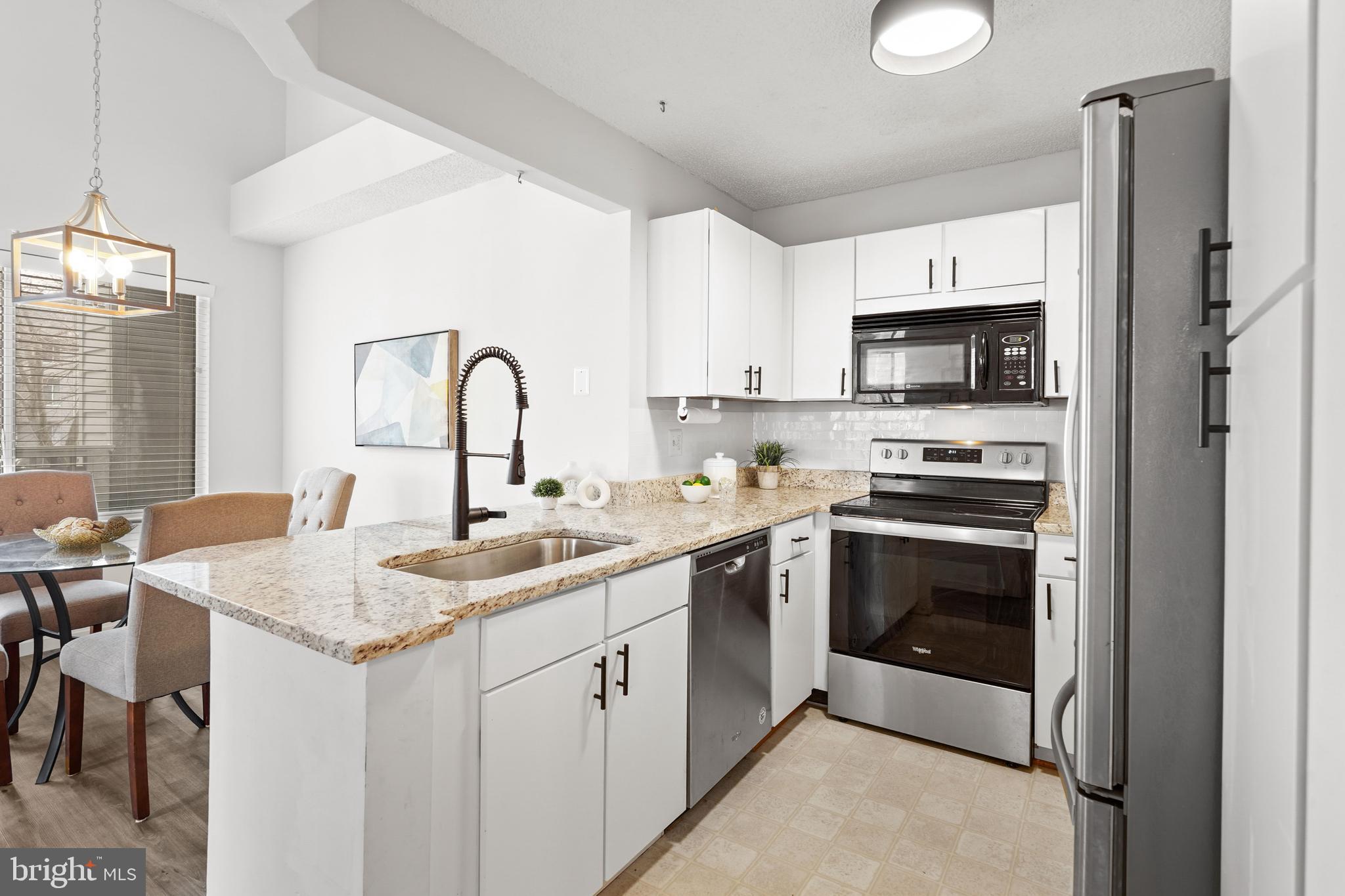 11731 Summerchase Circle, Unit 1731E Reston, VA 20194 - Photo 9 of 30 a kitchen with stainless steel appliances granite countertop a sink stove and refrigerator