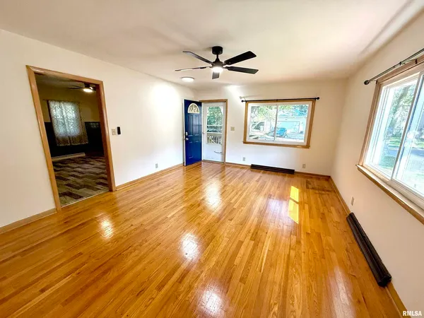 a view of an empty room with wooden floor and a window
