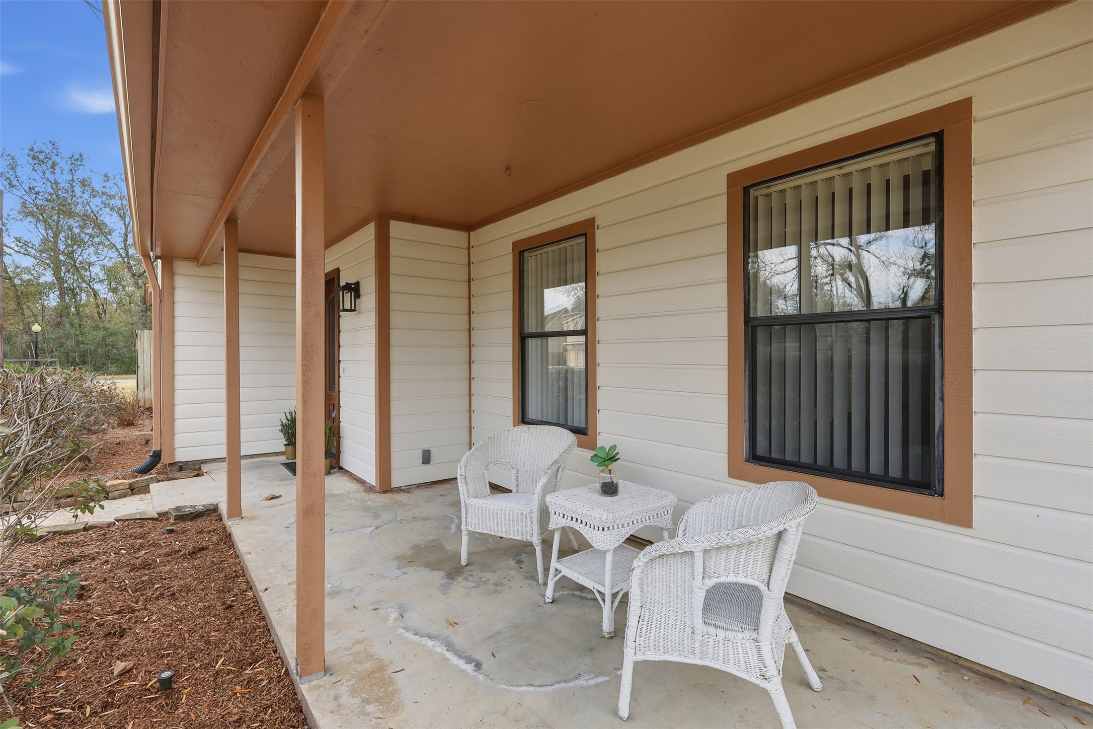 614 Tallow Drive Conroe, TX 77385 - Photo 2 of 36 Charming front porch with a covered area, featuring white wicker patio furniture. The space is inviting for relaxation and overlooks a neat garden area.