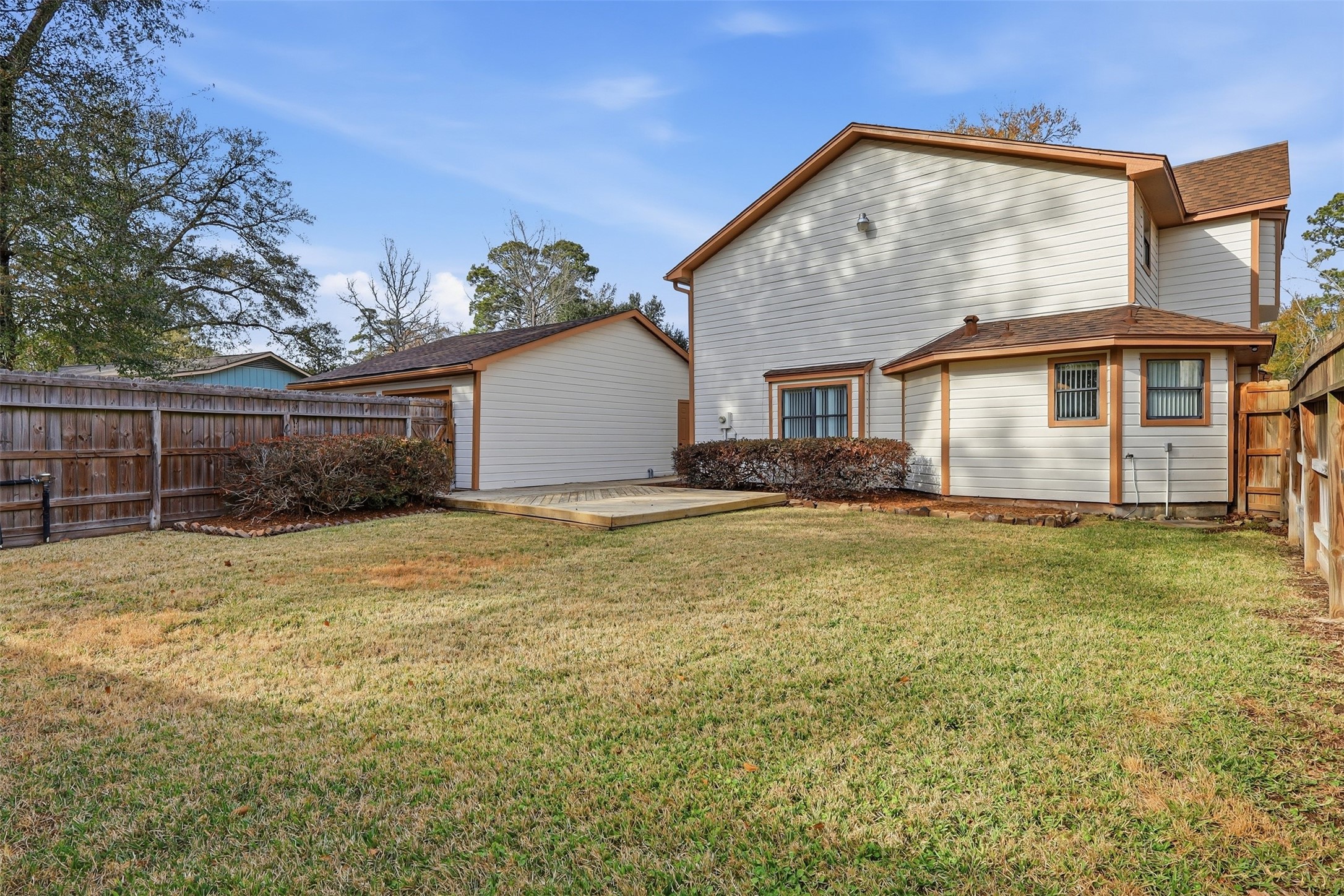 614 Tallow Drive Conroe, TX 77385 - Photo 35 of 36 well-maintained lawn, wooden fencing for privacy, and a small deck area. The house features a light exterior with brown trim, offering a clean and inviting look. Ideal for outdoor activities and relaxation.