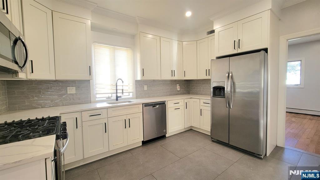164 Main Street, Unit 1 Garfield, NJ 07026 - Photo 5 of 14 a kitchen with white cabinets and white appliances