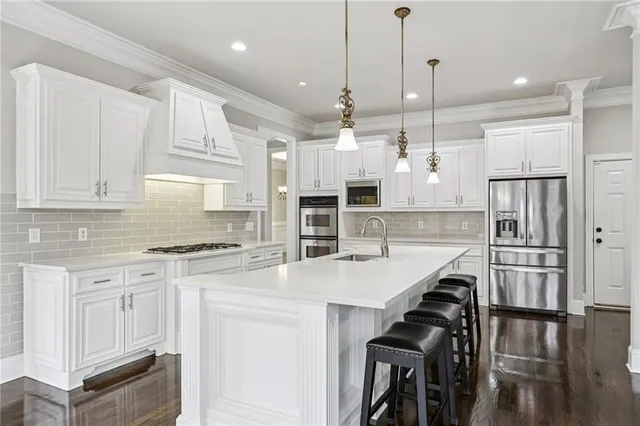 a open kitchen with granite countertop a stove top oven a dining table and chairs with wooden floor