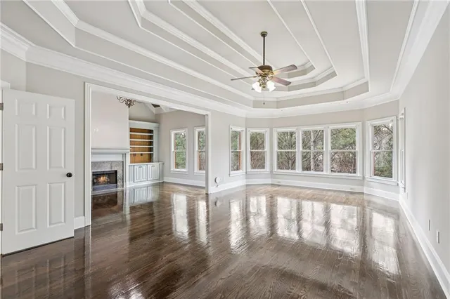a view of an empty room with wooden floor and a ceiling fan