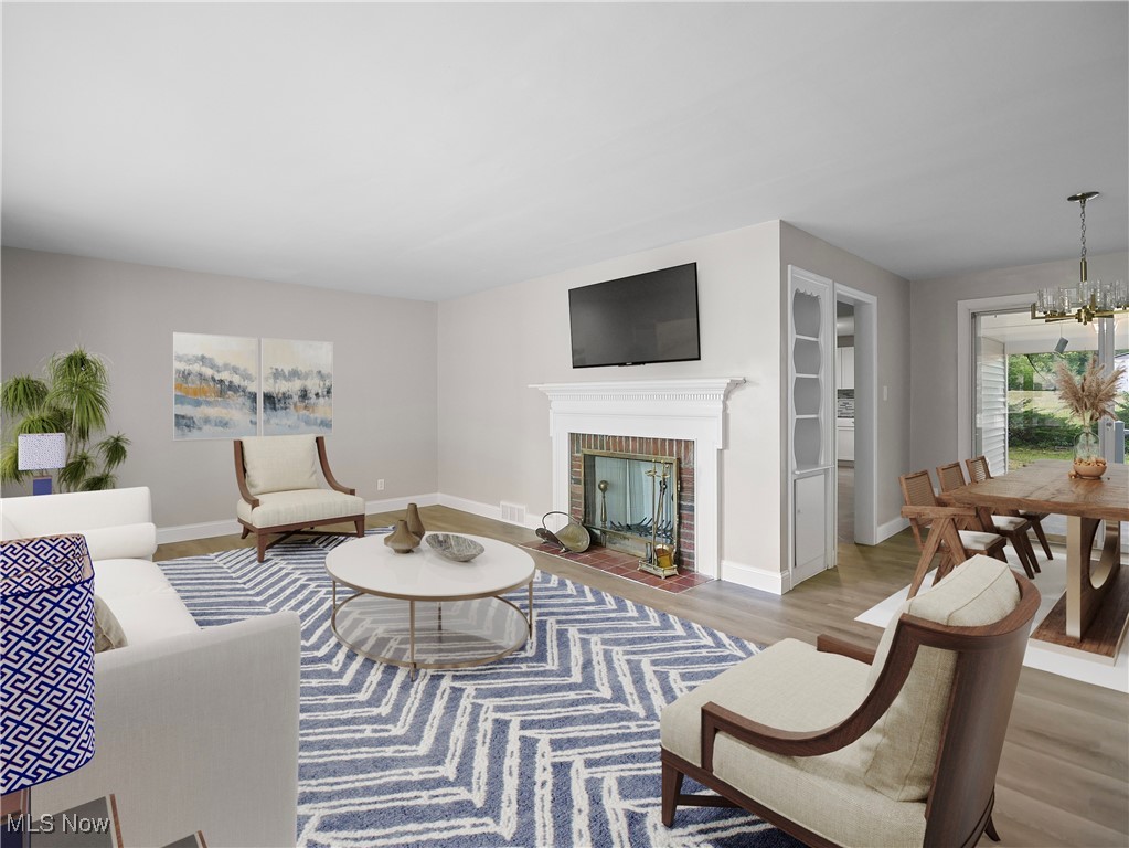 Living room with hardwood / wood-style floors, a chandelier, and a brick fireplace
