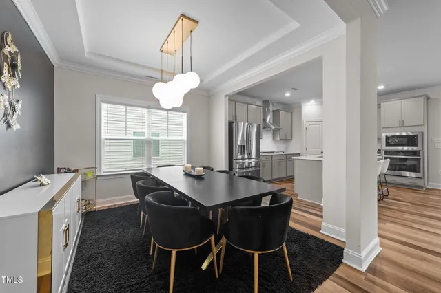 a dining room with wooden floor a chandelier a wooden table and chairs