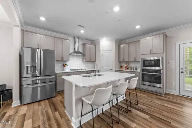 a kitchen with stainless steel appliances granite countertop a white refrigerator a sink dishwasher and a stove with wooden floor