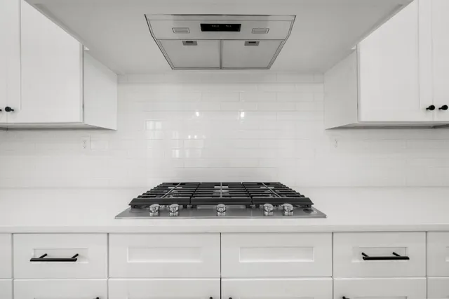 a large kitchen with kitchen island a stove a sink a center island and a wooden floor