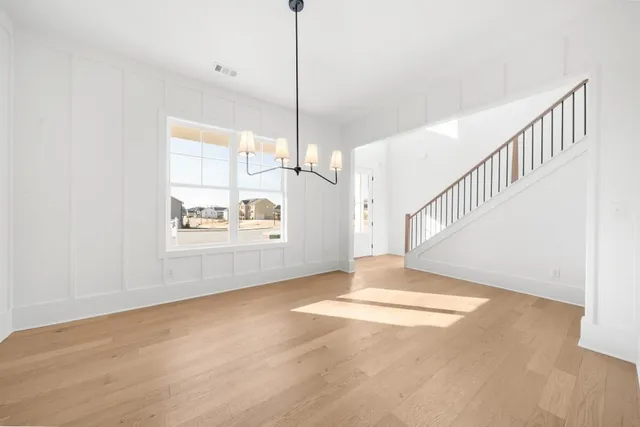 a large kitchen with stainless steel appliances kitchen island granite countertop a refrigerator a sink dishwasher a stove and white cabinets with wooden floor