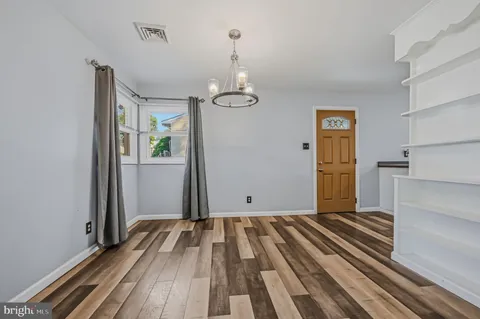 a view of a room with wooden floor kitchen appliances and windows