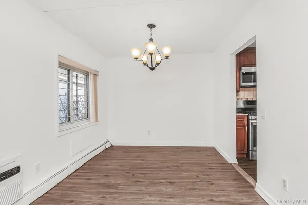 an empty room with wooden floor cabinet and windows
