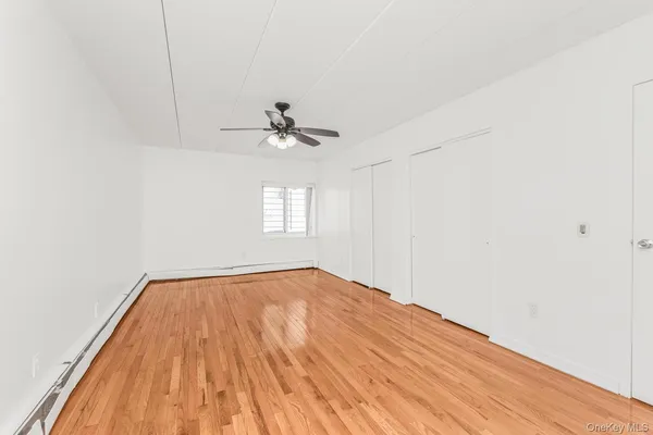 a view of empty room with window and chandelier fan