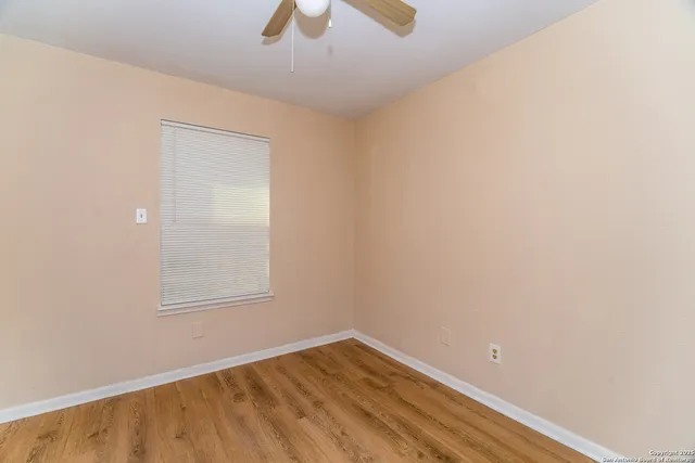 an empty room with a window and chandelier fan
