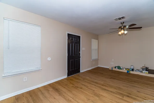 a view of a room with a hanging light and hardwood