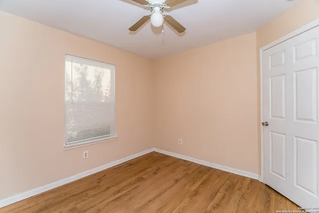 an empty room with a window and a ceiling fan