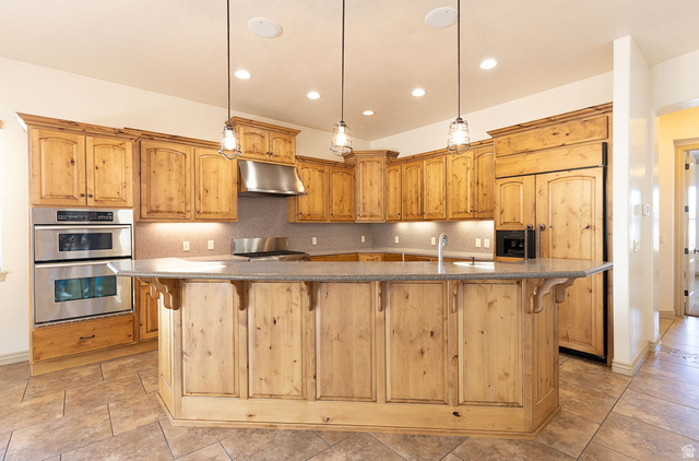 888 East Fiddlers Canyon Road Cedar City, UT 84721 - Photo 15 of 74 Kitchen with a spacious island, a breakfast bar area, stainless steel appliances, and decorative backsplash