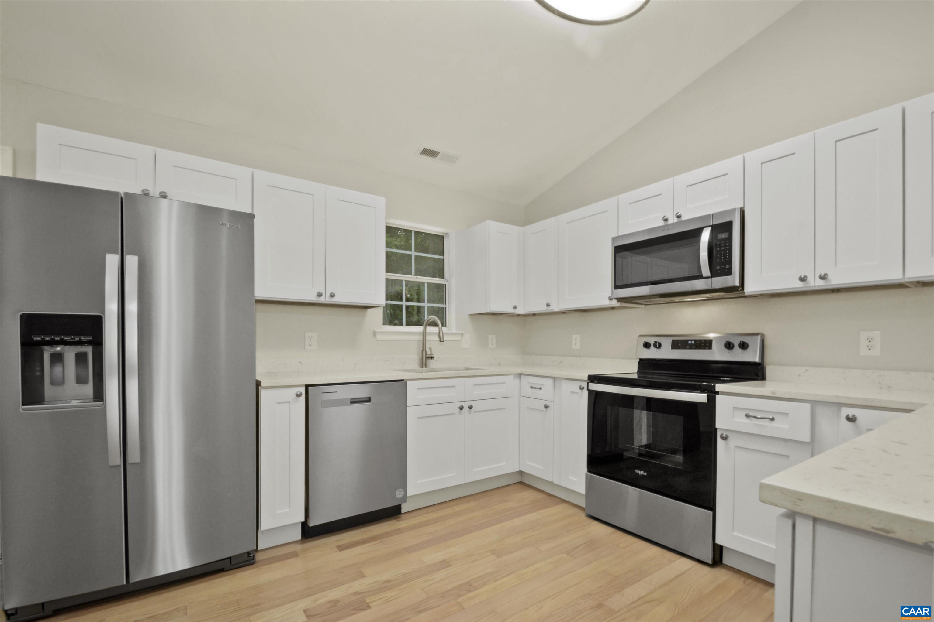 263 Morning Glory Road Ruckersville, VA 22968 - Photo 5 of 24 a kitchen with stainless steel appliances granite countertop a stove top oven a refrigerator and white cabinets with wooden floors
