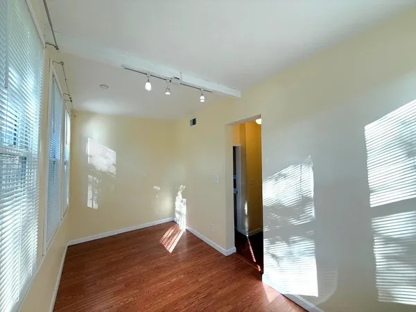 a view of empty room with wooden floor and windows