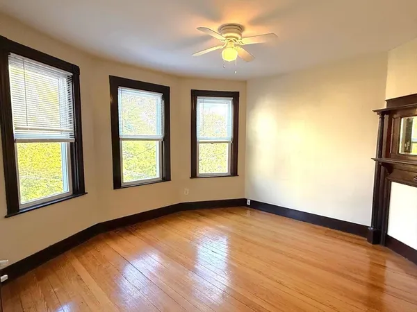 a view of an empty room with a window and wooden floor