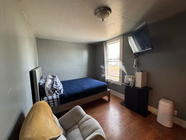 a view of a hallway with wooden floor and a bathroom