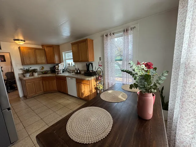a kitchen with a sink dishwasher a dining table and chairs with wooden floor