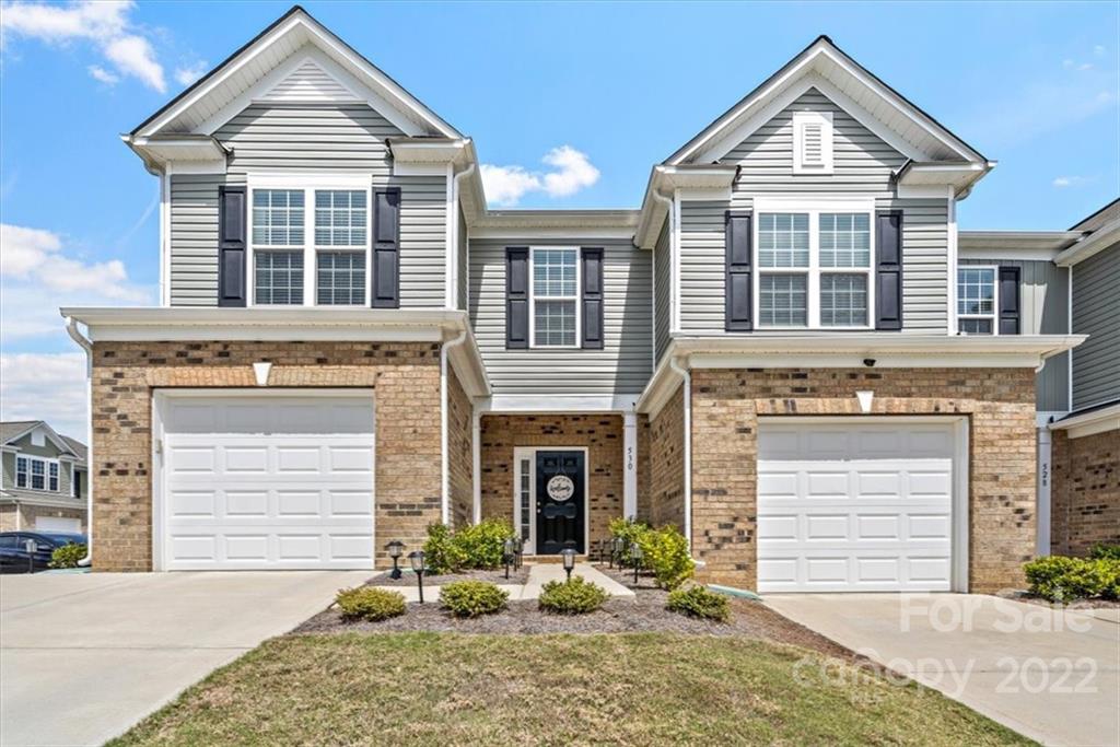 a front view of a house with yard and parking
