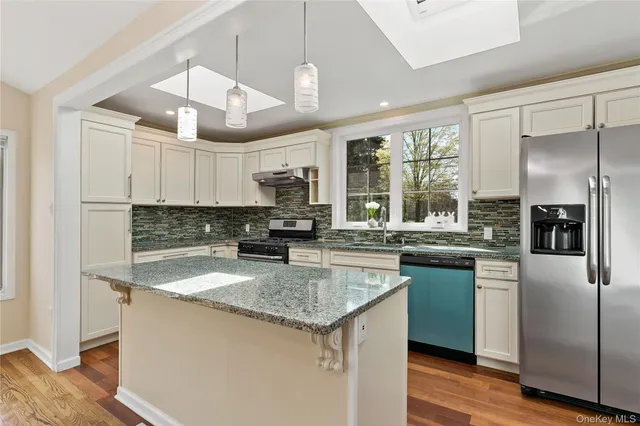 a kitchen with stainless steel appliances granite countertop a sink a stove and refrigerator