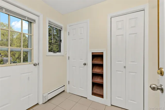 an entryway with wooden floor closet and windows