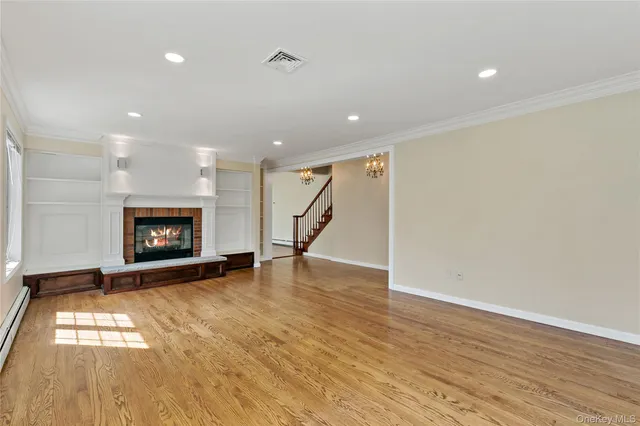 a view of an empty room with wooden floor and a fireplace