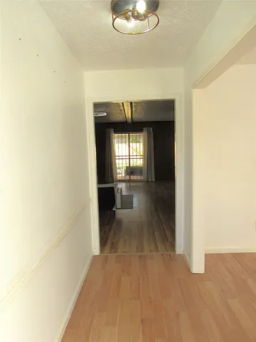 a view of a hallway with wooden floor and a chandelier