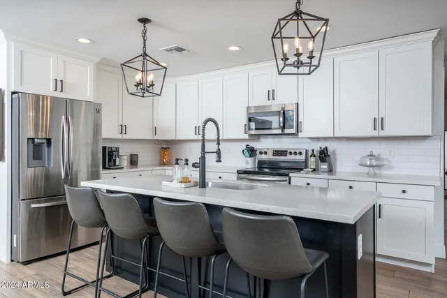 a kitchen with stainless steel appliances a table chairs refrigerator and microwave