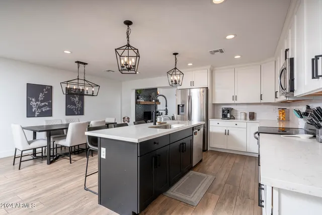 a kitchen with a stove a refrigerator a sink dishwasher a dining table and chairs with wooden floor