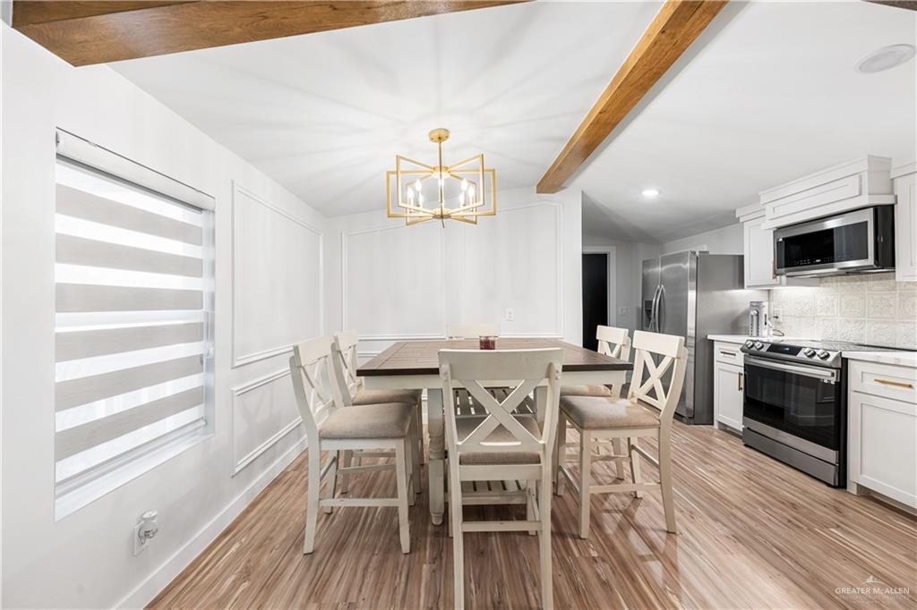 5501 Mile 8 1/2 Road Edinburg, TX 78541 - Photo 7 of 36 Dining area with light wood finished floors, a decorative wall, vaulted ceiling with beams, and a chandelier