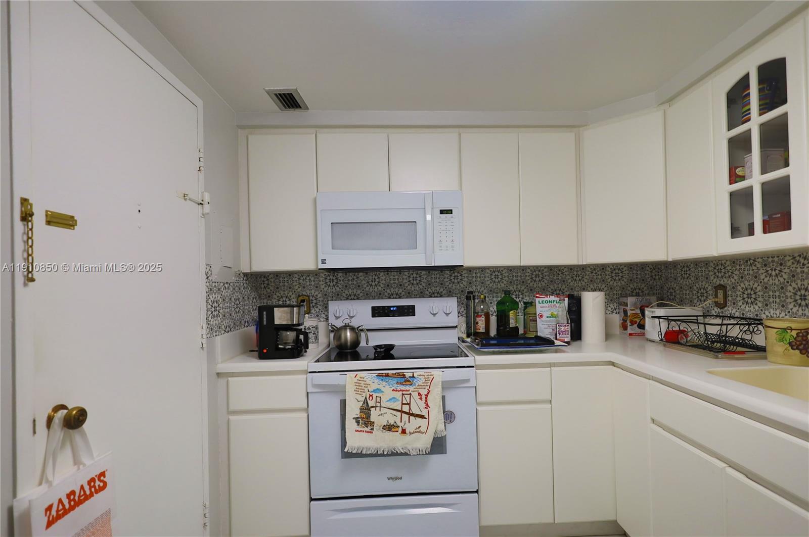 9225 Collins Avenue, Unit PHC Surfside, FL 33154 - Photo 32 of 33 a kitchen with white cabinets and white appliances