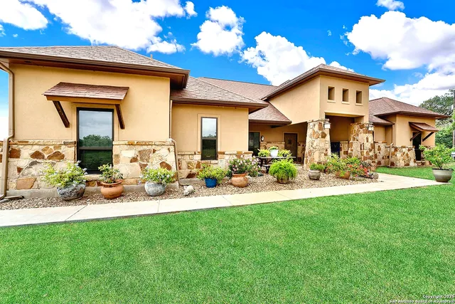 a front view of a house with a yard and potted plants