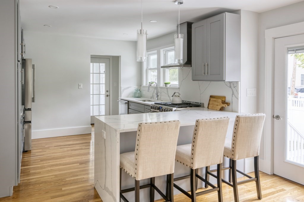 1 Mary Street, Unit 1 Arlington, MA 02474 - Photo 9 of 27 a kitchen with stainless steel appliances kitchen island granite countertop a table chairs sink and cabinets