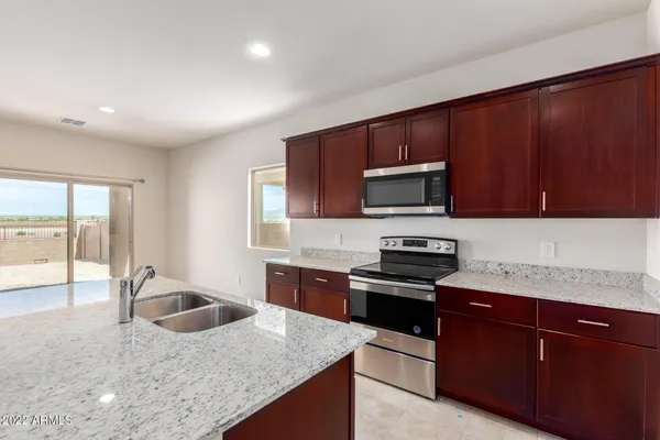 a kitchen with granite countertop wooden cabinets a stove and a microwave with granite countertops