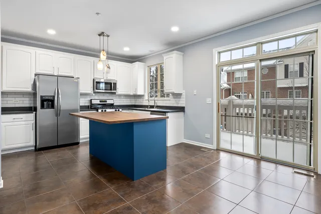 a kitchen with stainless steel appliances granite countertop a stove a sink a refrigerator and white cabinets with wooden floor