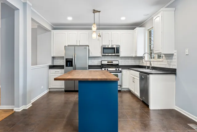 a kitchen with kitchen island granite countertop a sink a counter top space stainless steel appliances and cabinets