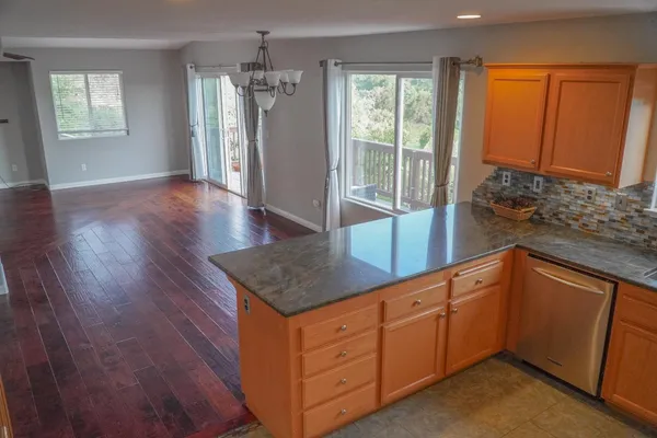 a kitchen with stainless steel appliances granite countertop a refrigerator a sink dishwasher and wooden cabinets with wooden floor
