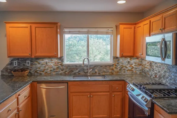 a kitchen with granite countertop a sink a counter top space and stainless steel appliances