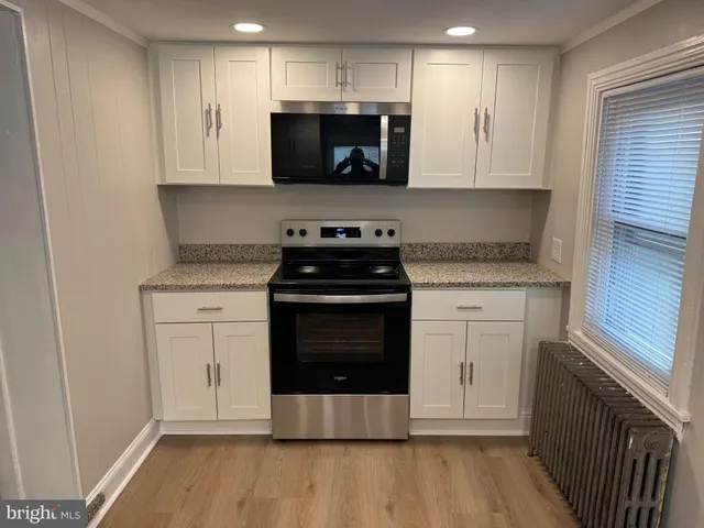 a kitchen with stainless steel appliances granite countertop a stove a microwave and a white cabinets