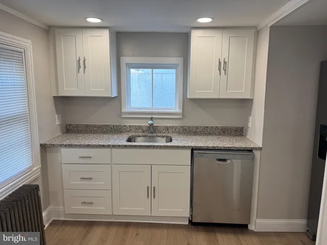 a kitchen with granite countertop white cabinets and a sink