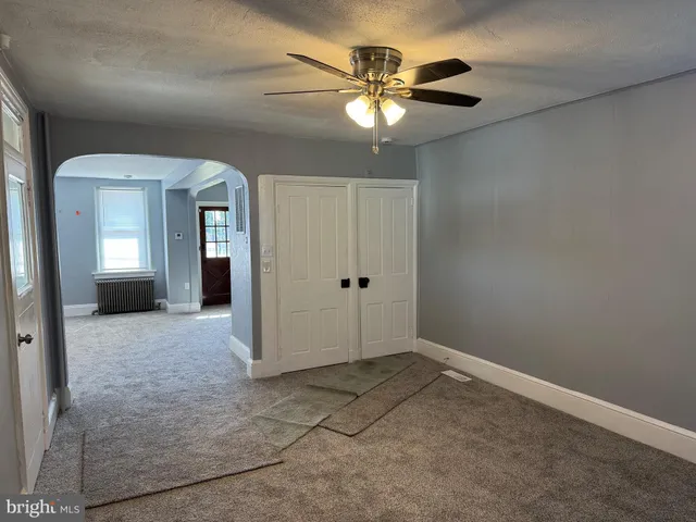 wooden floor in an empty room with a chandelier fan