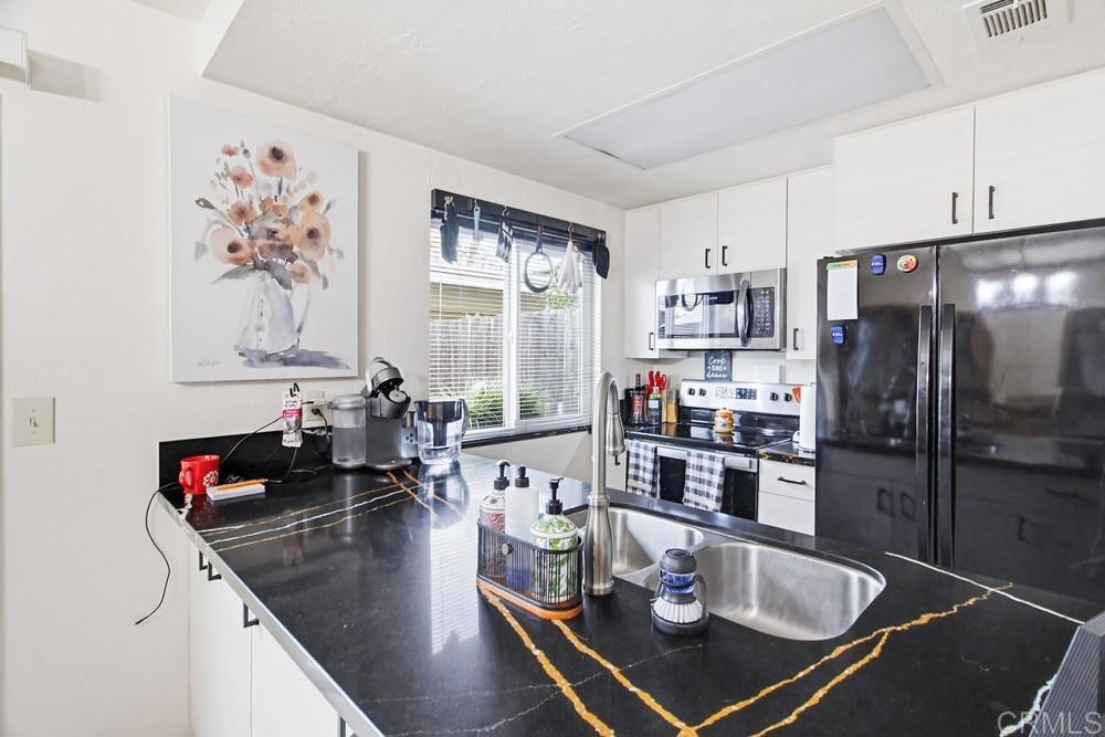 7861 Rancho Fanita Drive, Unit B Santee, CA 92071 - Photo 11 of 47 a kitchen with stainless steel appliances granite countertop a refrigerator a stove and white cabinets with wooden floor