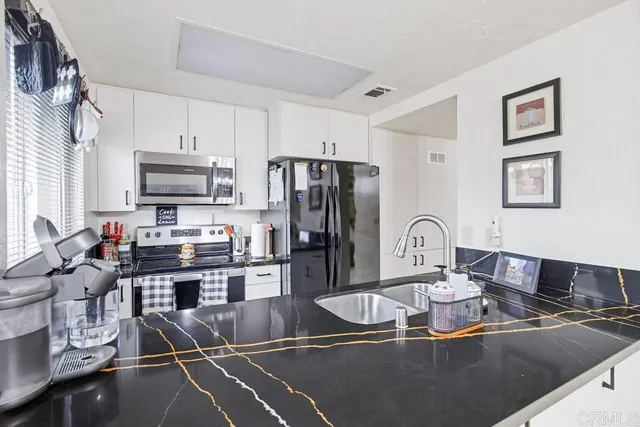 a kitchen with kitchen island granite countertop a sink appliances cabinets and a counter top space