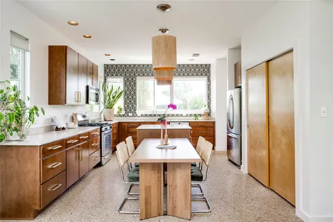 a kitchen with stainless steel appliances a dining table and chairs
