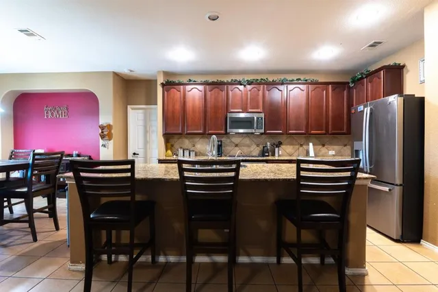 a kitchen with kitchen island granite countertop wooden cabinets and stainless steel appliances