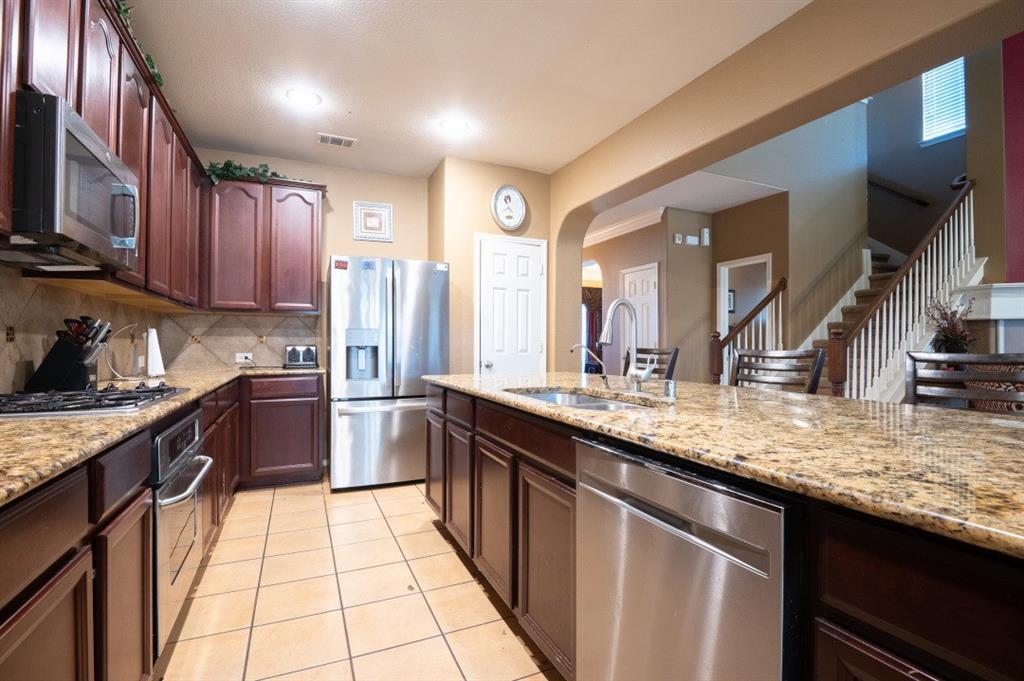 2248 Condor Street Grand Prairie, TX 75052 - Photo 22 of 25 a kitchen with stainless steel appliances granite countertop a sink stove and refrigerator